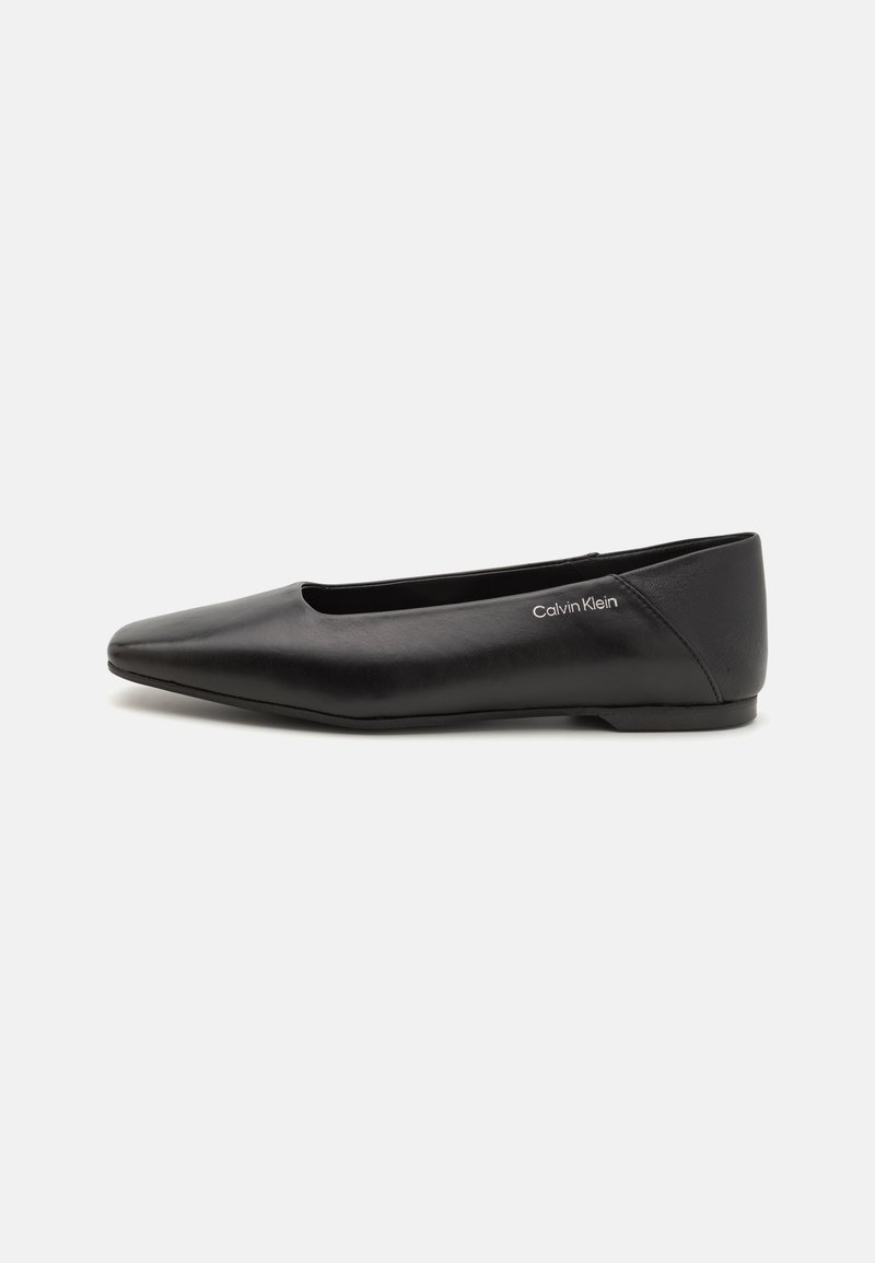 Bailarina de cuero negro con punta afilada y costuras mínimas. Presenta una textura suave y una suela plana, con la marca 'Calvin Klein' en el lado.