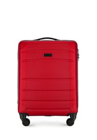 Valigia rigida rossa con superficie testurizzata, cerniere nere e manico superiore. Dotata di quattro ruote nere per la mobilità. Logo del brand visibile.