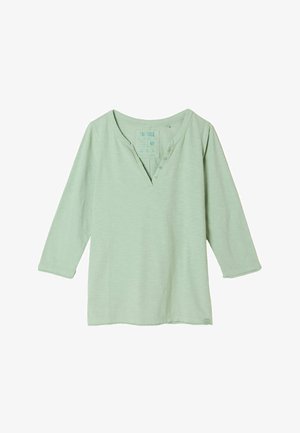 Hellgrünes Langarmhemd mit V-Ausschnitt und vier Knöpfen an der oberen linken Seite des Halsausschnitts, aus weichem Stoff gefertigt.