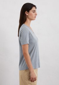 Lichtgrijze v-hals t-shirt met korte mouwen, gemaakt van zacht materiaal. Heeft een losse pasvorm en een gladde textuur.