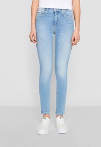 Ljusblå smala jeans i denim med en slät textur. Har en medelhög midja, fem fickor och knäppning med knapp.