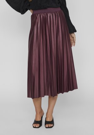 Pflaumenfarbener, plissierter Midirock mit weicher Textur und breitem Bund. Tragen Sie dazu offene schwarze Mules, die ein sauberes und elegantes Design zeigen.