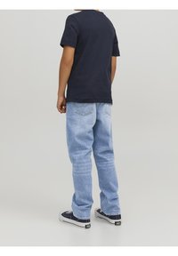 Marinblå bomullströja i avslappnad passform, parat med ljusblå denimjeans med klassisk femfickdesign, matchat med svarta sneakers.