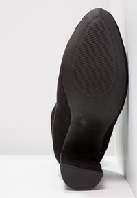 Schwarze Wildleder-Stiefelette mit spitzem Zehenbereich, niedrigem Absatz und strukturiertem Gummisohle. "NEW LOOK"-Markierung an der Seite des Absatzes sichtbar.