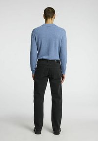 Light blue knit sweater with collar paired with black jeans. Sweater has a soft texture; jeans feature back pockets and straight leg design.