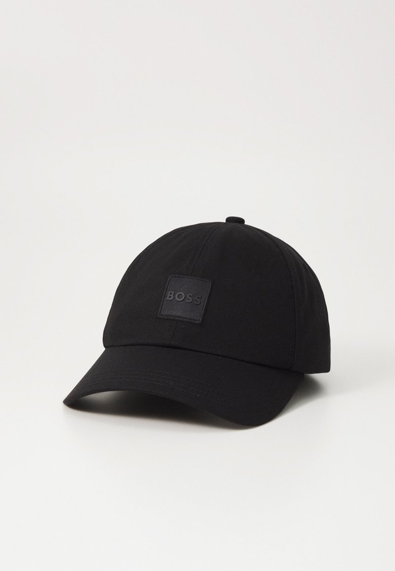 Casquette de baseball noire avec une visière incurvée et un petit patch carré sur le devant affichant le mot "BOSS" en noir assorti.