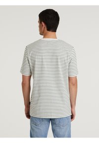 T-shirt a maniche corte a righe bianco e verde scuro, con collo rotondo e orlo dritto. Realizzato in tessuto morbido con una texture leggera.