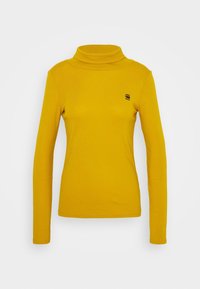 Gelbes Langarm-Turtleneck-Oberteil aus weichem Stoff, mit taillierter Passform und kleinem schwarzem Logo auf der Brust. Glatte Textur.