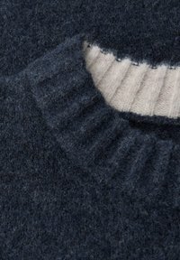 Dunkelblauer Strickpullover mit einem gerippten Kragen und cremefarbener Streifen; weiche Textur mit einem erhabenen Musterdetail.