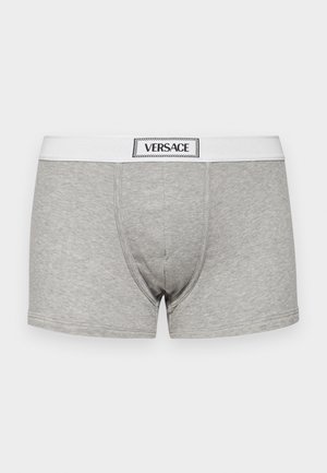 Boxer-culottes gris en tissu texturé assorti, avec une ceinture élastique blanche portant l'inscription "VERSACE."