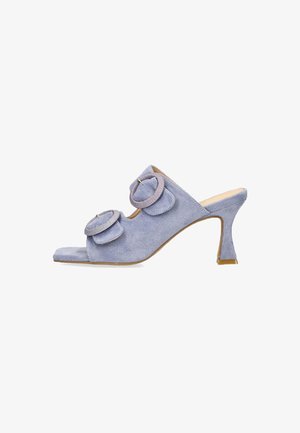 Mules de ante lavanda con tacón, que presentan dos acentos de tela en forma circular, un diseño de punta abierta y un tacón alto y afinado. Textura suave con un acabado liso.