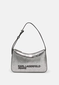 Silver metallic shoulder bag with a curved shape, smooth texture, and black logo text. Features a thin strap and zip closure.