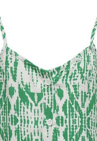 Haut en tissu à motifs verts et blancs avec des bretelles fines, doté d'une patte de boutonnage et d'une coupe ample. Design texturé avec des formes abstraites.