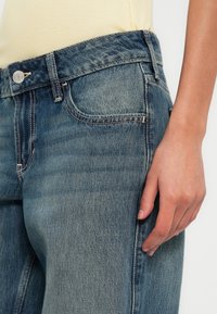 Džínsy z denimu so svetlomodrým vyblednutým prevedením, priamym strihom, dizajnom s piatimi vreckami a kontrastným prešívaním.