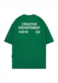 Camiseta verde de gran tamaño con "DEPARTAMENTO CREATIVO" en texto blanco, con cuello redondo y mangas cortas. "®2018 CD" impreso abajo.