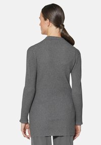 Grijze geribbelde lange mouwen trui met een hoge kraag en zijsplitten. Materiaal: zachte tricot met een gestructureerd patroon.