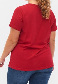 Rød kortærmet t-shirt med rund halsudskæring, lavet af blød bomuld, med en afslappet pasform og en let buet kant bagpå.