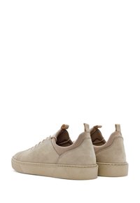 Sneakers in suede beige con una superficie liscia, punta arrotondata, suola in gomma piatta e pratiche linguette sul tallone per una facile calzata.
