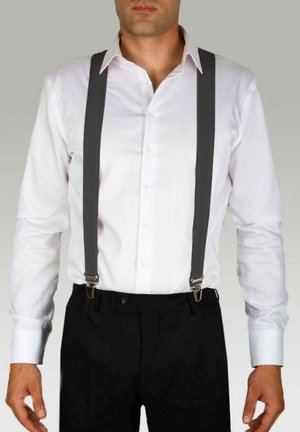 Chemise blanche à manches longues avec des bretelles grises, dotée de quincaillerie en argent. La chemise a un col classique et une fermeture à boutons, associée à un pantalon noir.