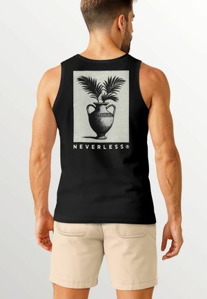 A man wearing a black tank top with a plant in a vase graphic on the back, standing against a light background.