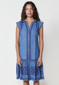 Un vestito di jeans con maniche corte a cappuccio, una chiusura frontale con bottoni e ricami decorativi lungo il corpetto e l'orlo in un colore blu.