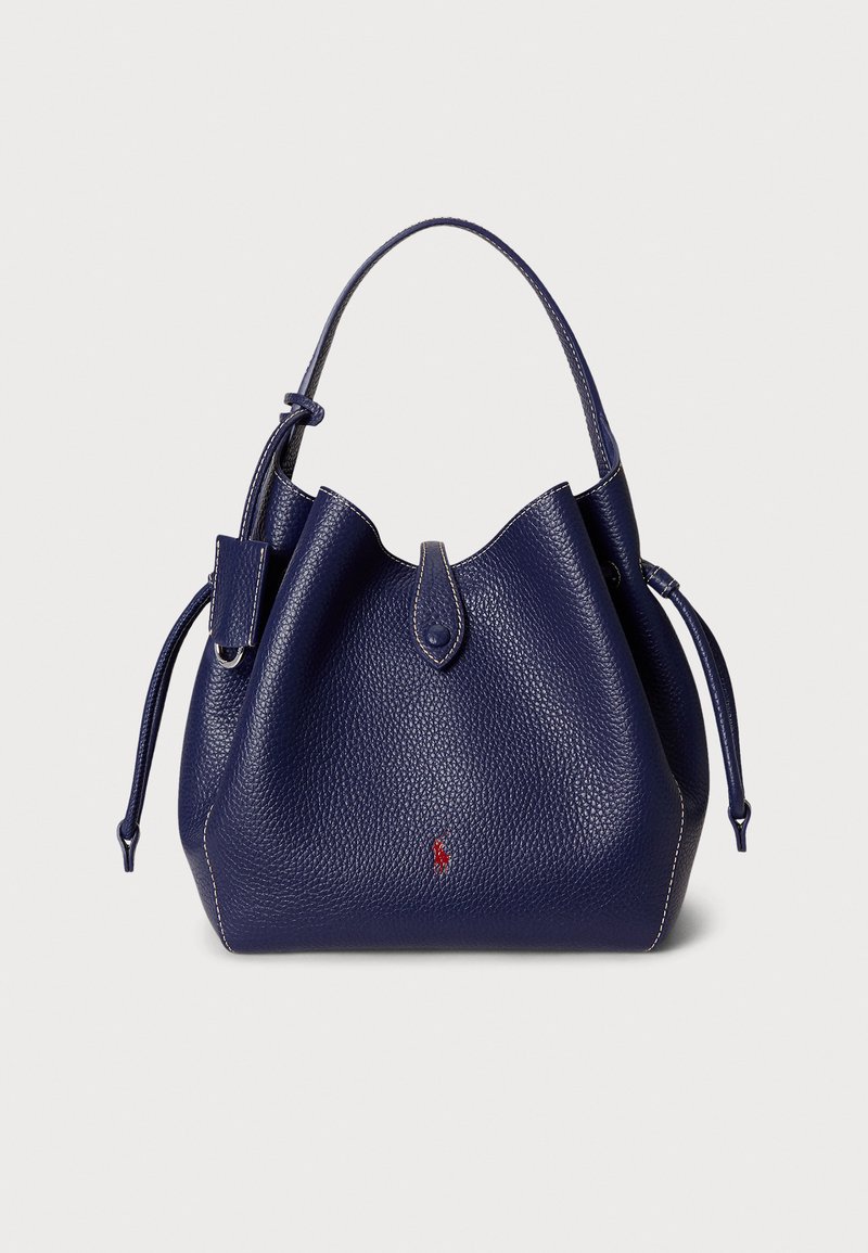 Laivastonsininen nahkainen säilytyspussi, jossa on teksturoidu viimeistely, kiristysnyöri ja lyhyt kahva. Edessä pieni punainen logon yksityiskohta.