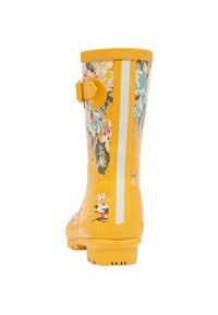 Bota de lluvia de goma amarilla con patrón floral, franja vertical blanca, agarre texturizado en la parte superior. Presenta un detalle de hebilla en el costado.