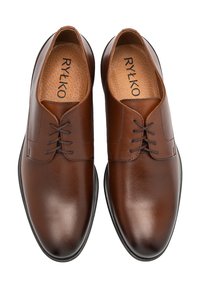 Zapatos de vestir de cuero marrón con una superficie lisa y brillante. Presentan un cordón tradicional y una forma de punta redondeada. El forro interior es texturizado.