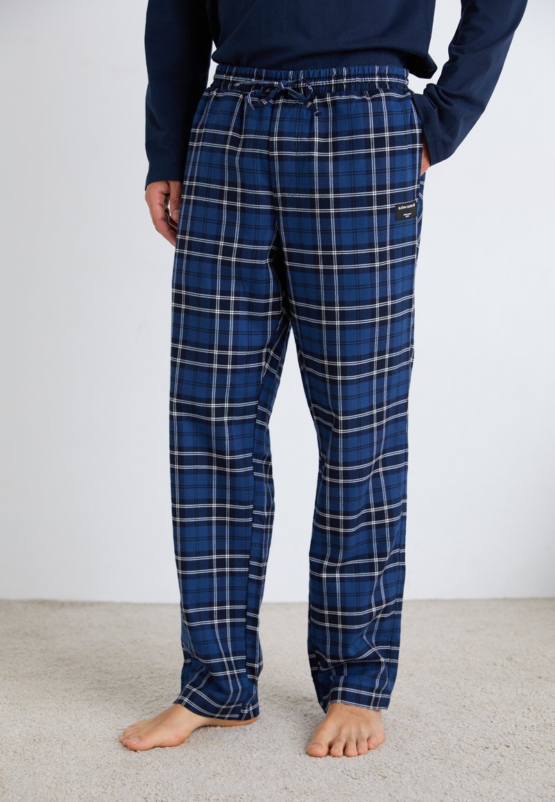 Pantaloni scurți de pijama în carouri albastre, dintr-un material moale, având un cordon la talie, buzunare laterale și accente albe în modelul în carouri.
