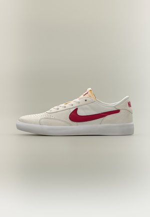 Бяла ниска маратонка Nike с червено лого Swoosh и бяла подметка, показана в профил на изчистен фон.
