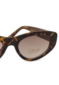 Lunettes de soleil écaille de tortue marron de forme œil de chat avec verres dégradés. Elles offrent une protection UV 400 et portent le marquage CE sur le verre.