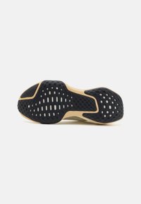 Fekete gumírból készült sneaker talp, textúrázott tapadási mintázattal, világos bézs középtalppal és fehér akcentusokkal a tapadás és a rugalmasság érdekében.