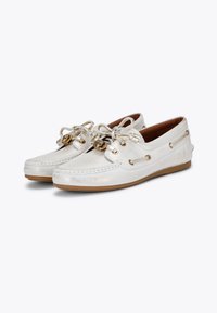 Scarpe da barca in pelle bianca con finitura metallica, dotate di lacci decorativi, accenti in metallo dorato e suola in gomma color tan.