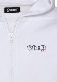Sudadera blanca con cremallera y una textura suave. Presenta una cremallera frontal y un logo en azul y rojo en el pecho. Diseño sencillo.