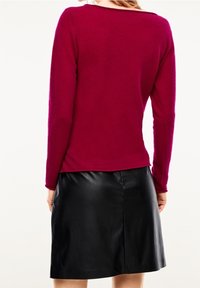 Magenta sweter z długimi rękawami, okrągłym dekoltem i miękką teksturą, w połączeniu z czarną skórzaną spódnicą do kolan o gładkim wykończeniu.