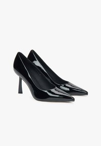 Zwarte gepatineerde leren high heel pumps met spitse neuzen en een elegante silhouet. Bevat een stiletto hak en een gladde binnenvoering.