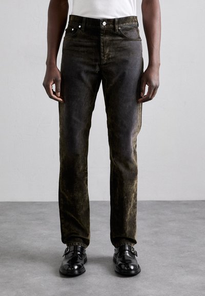 Black distressed jeans with a faded finish, five pockets, and a straight leg design, paired with black shoes.