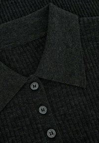 Polo noir à côtes avec une texture douce, doté d'un col classique et de quatre boutons noirs le long de la patte de boutonnage.