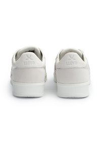 Białe trampki z gładką cholewką ze skóry i zamszu, subtelnym logo na pięcie oraz teksturowaną białą gumową podeszwą.