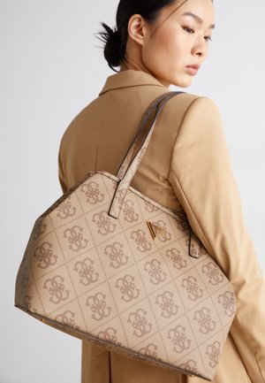 Sac à main beige à motifs avec deux poignées, design géométrique, texture lisse et logo doré sur un côté.