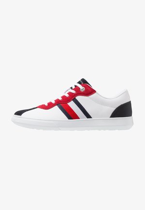 Biały niskoprofilowy sneaker z czerwonymi zamszowymi dziurkami na sznurówki, czarnymi akcentami na nosku i pięcie oraz czerwono-biało-niebieskimi paskami po boku.