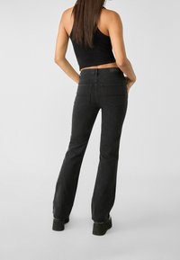 Zwarte flare jeans van denim, met een hoge taille, minimale stiksels en twee achterzakken, aangevuld met een gestructureerd zwart label.