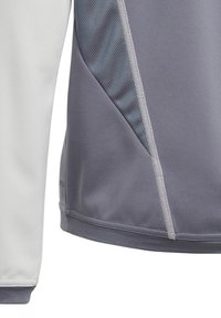 Grijs en wit sportshirt met een gestructureerd grijs paneel, gladde stof, contrasterende platte naden en ademende mesh details.