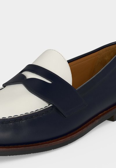 Loafery z granatowej i białej skóry z paskiem na pieniądze, przeszywany czubek, wnętrze z beżowej skóry oraz brązowa podeszwa z czarnym gumowym spodem.