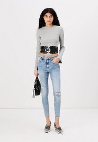 Pelēkais ribots garām piedurknēm tops, melns plats jostas siksna ar sudraba sprādzi, gaiši zili plandoši skinny džinsi, melna rokassoma, sudraba augstpapēžu kurpes.