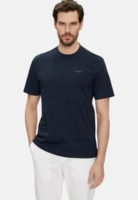 T-shirt in cotone blu navy con maniche corte e collo rotondo, caratterizzato da un piccolo logo ricamato sul petto. Texture liscia.