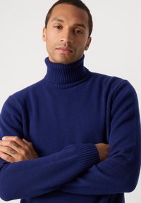Dunkelblauer Rollkragenpullover aus weichem Strickstoff, mit geripptem Kragen und Bündchen, in passformbetonter Gestaltung und glatter Textur.