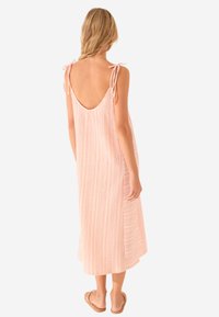 Abito midi rosa chiaro con una vestibilità rilassata, spalline regolabili, scollatura a forma di U e texture a righe verticali. Tessuto casual e traspirante.