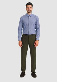 Hellblaues Hemd mit Knöpfen, kombiniert mit dunkelgrünen Hosen. Der Look wird mit schwarzen Schuhen vervollständigt. Glatter Stoff, maßgeschneiderte Passform.