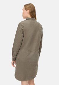 Robe chemise vert olive en tissu doux, dotée d'un col, de manches longues et d'un ourlet incurvé pour un ajustement décontracté.